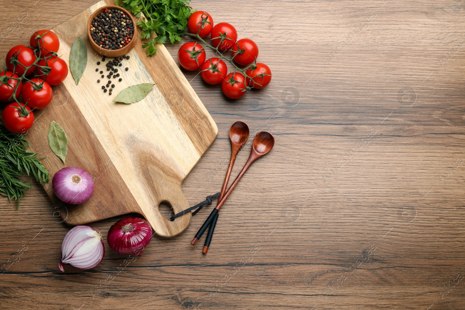 Photo of Cutting board and vegetables on wooden table, flat lay with space for text. Cooking utensils