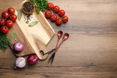 Cutting board and vegetables on wooden table, flat lay with space for text. Cooking utensils