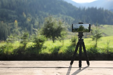 Photo of Taking photo of beautiful mountain landscape with smartphone mounted on tripod outdoors
