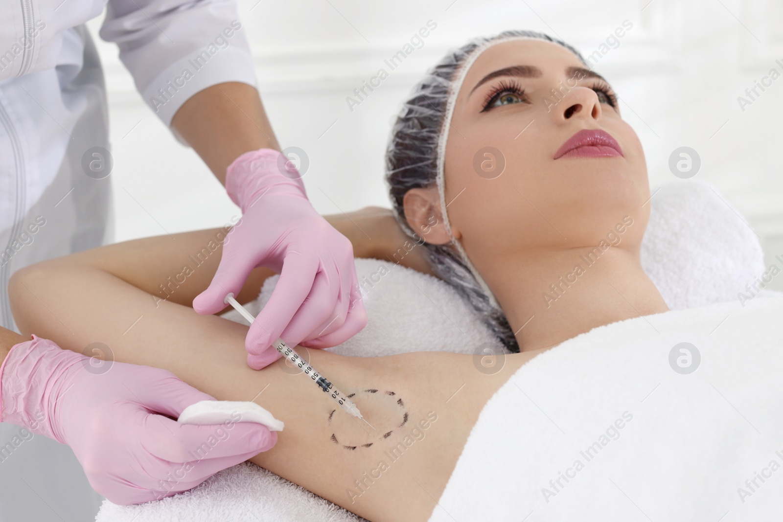 Photo of Cosmetologist injecting young woman's armpit in clinic. Treatment of hyperhidrosis