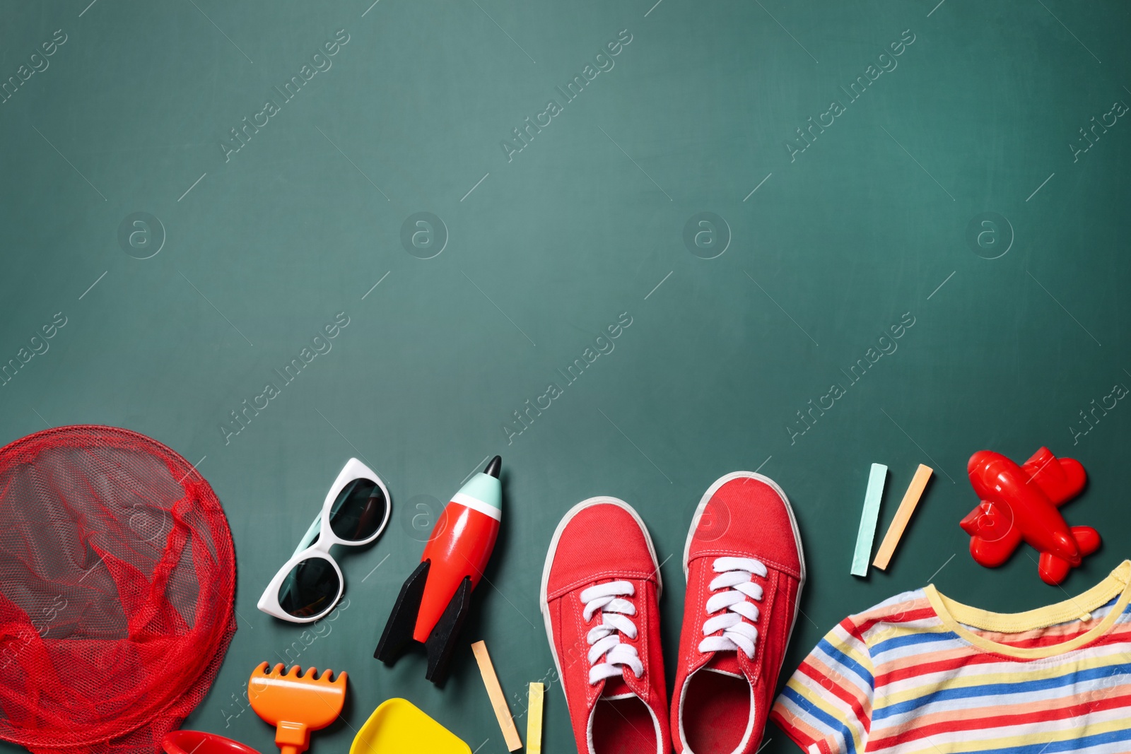 Photo of Different child accessories and space for text on green chalkboard, flat lay. School holidays