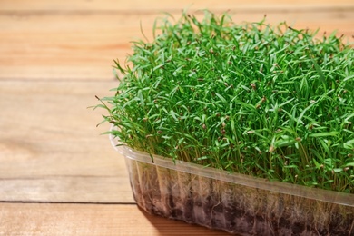 Photo of Fresh organic microgreen on wooden table, closeup