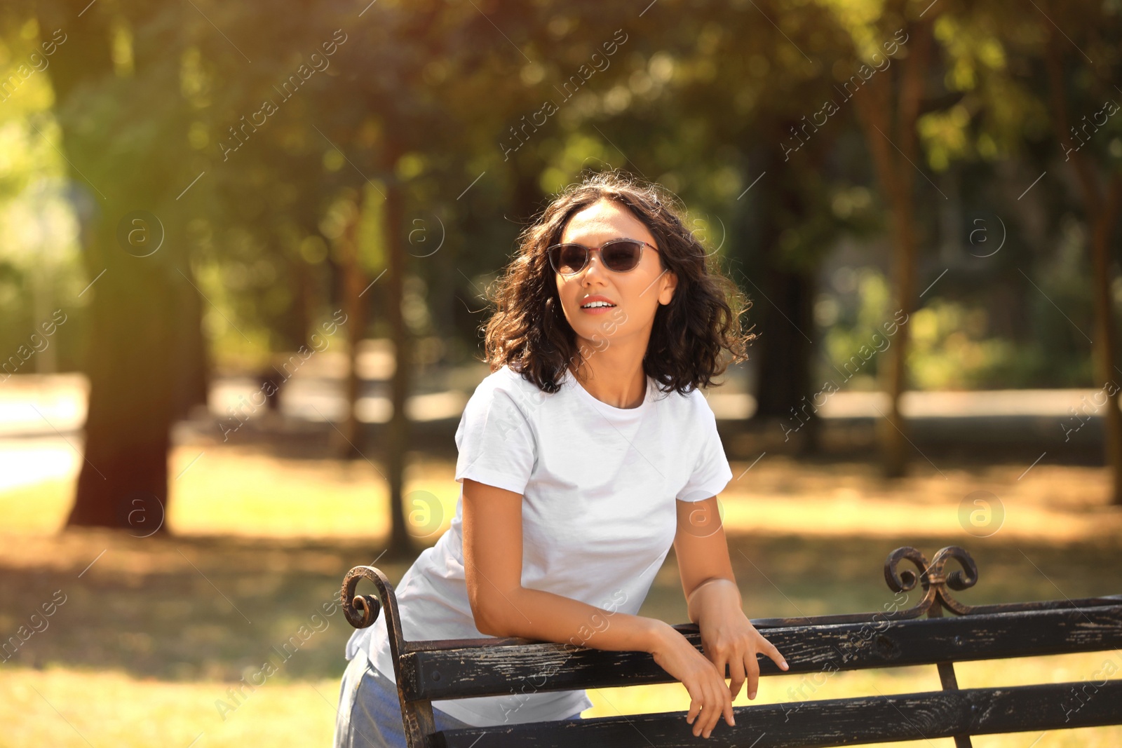 Photo of Beautiful young woman standing near bench in park