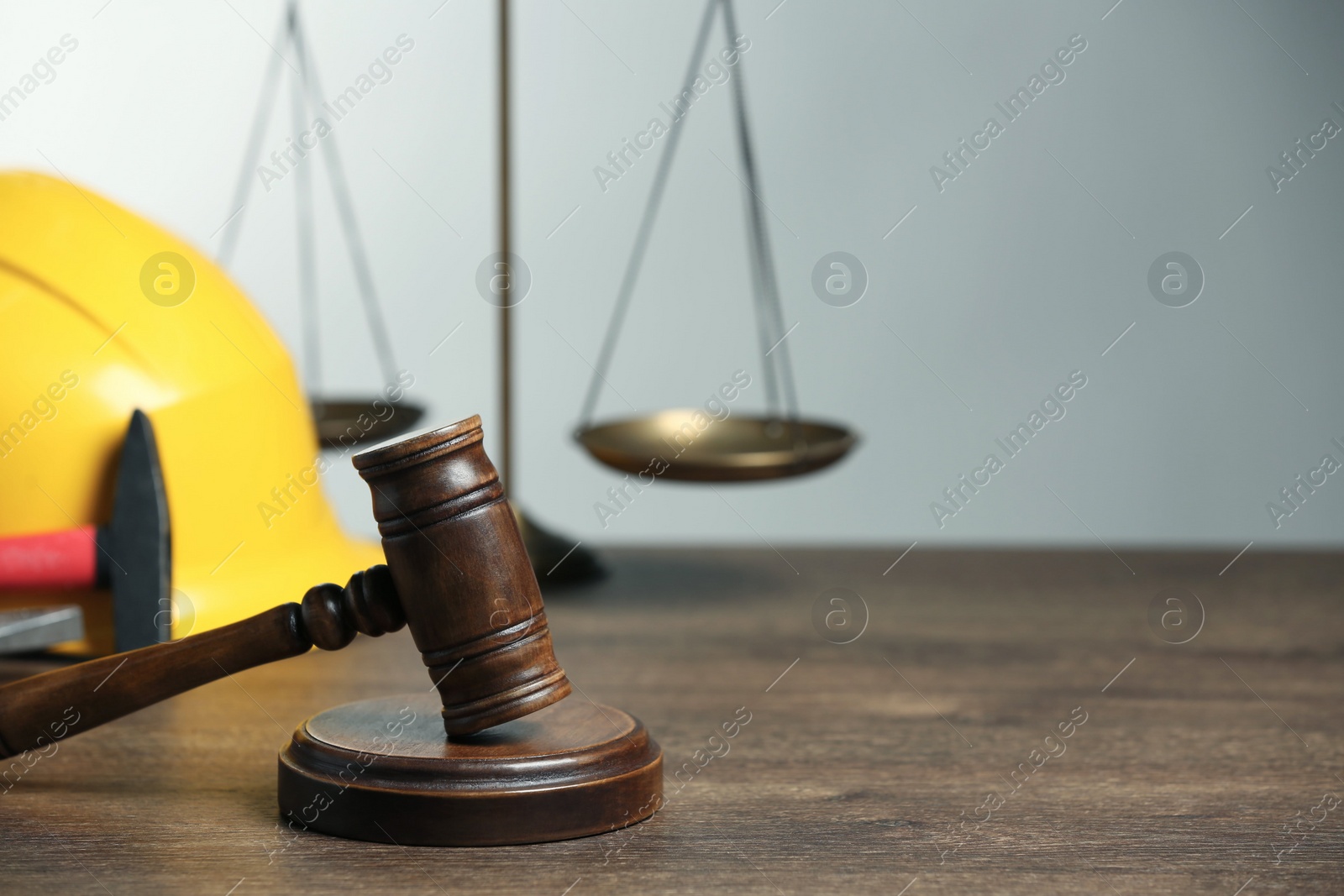 Photo of Construction and land law concepts. Gavel, scales of justice, hard hat and hammer on wooden table, space for text