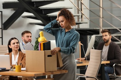 Photo of Young dismissed woman packing stuff into box at office