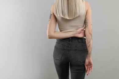Photo of Woman with cool tattoos on gray background, closeup. Space for text