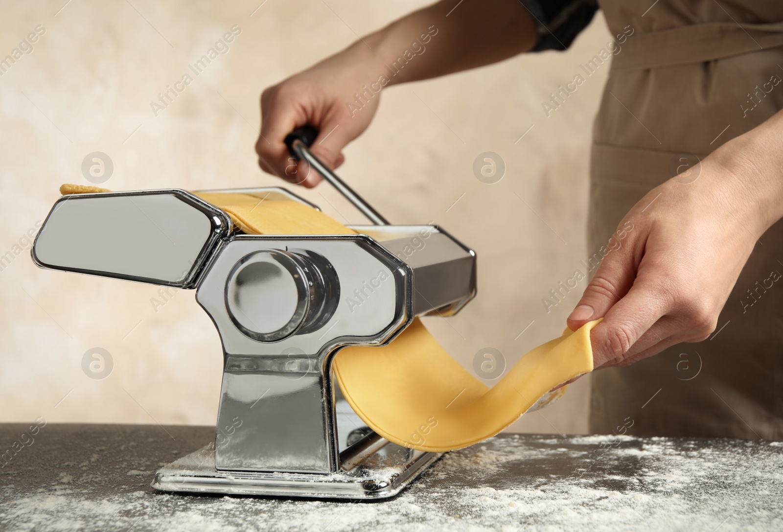 Photo of Woman preparing dough with pasta maker machine at table, closeup