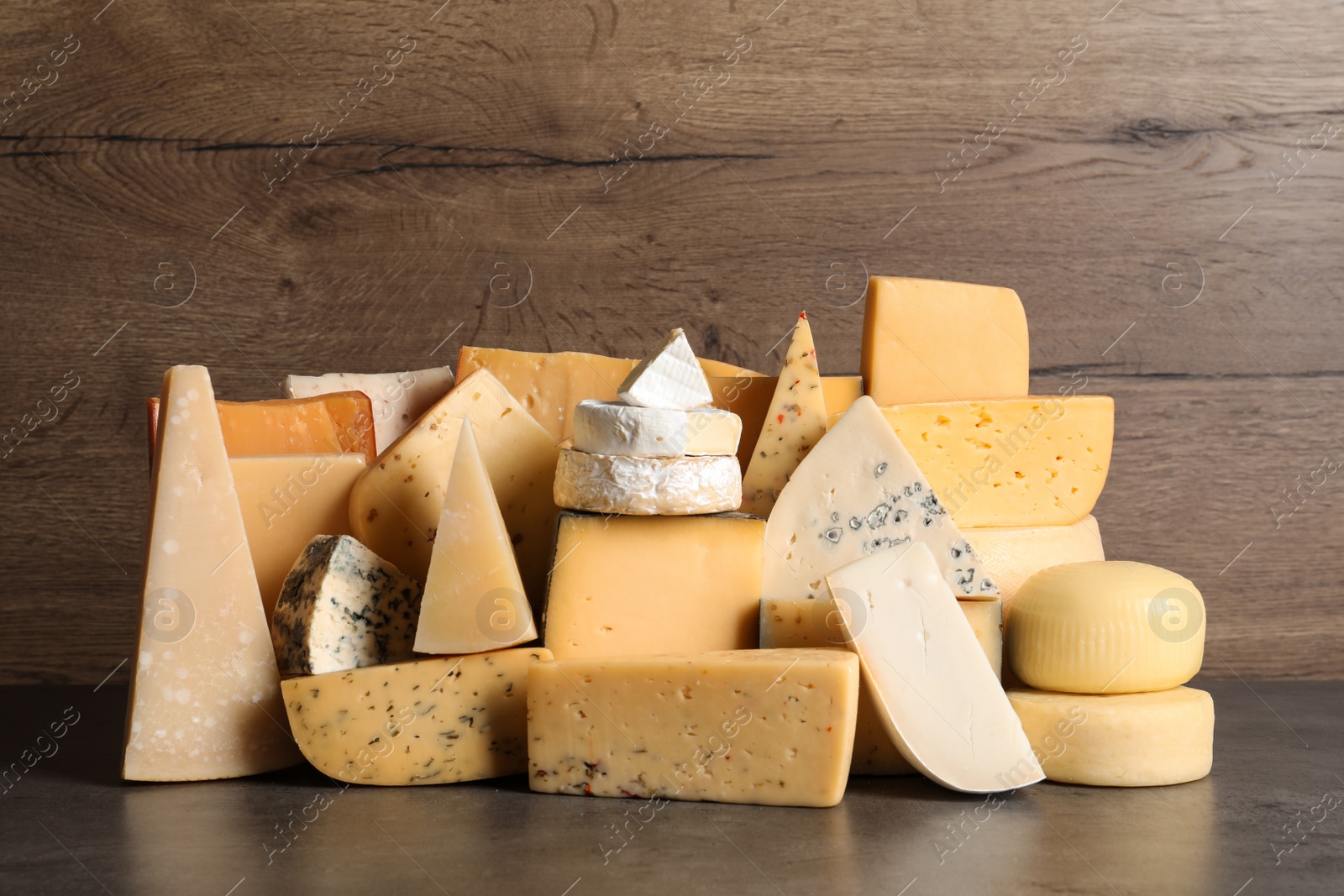 Photo of Different types of delicious cheese on table against wooden background