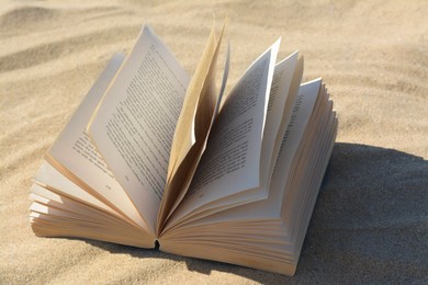 Open book at sandy beach on sunny day