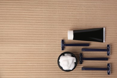 Different men's shaving accessories on brown corrugated cardboard, flat lay. Space for text