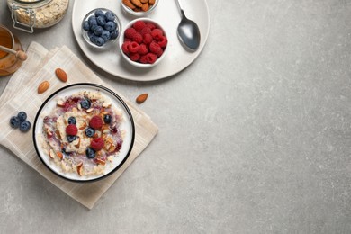 Photo of Tasty oatmeal porridge with toppings served on grey table, flat lay. Space for text