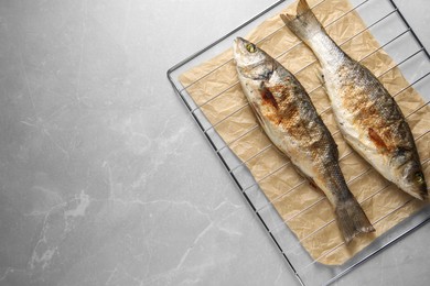 Photo of Baked fish on light marble table, top view. Space for text