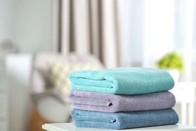 Photo of Stack of folded clean soft towels on table indoors. Space for text