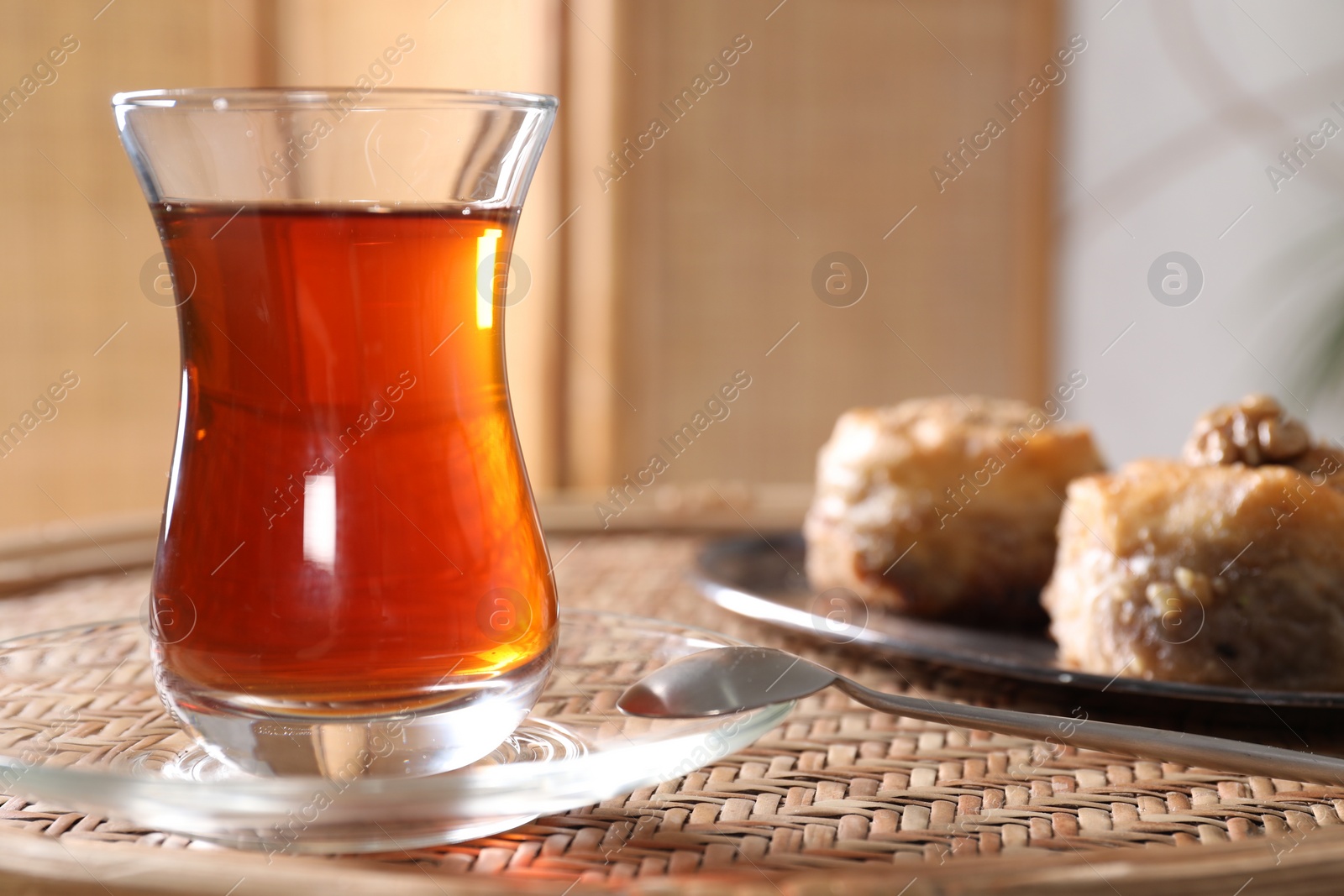 Photo of Traditional Turkish tea in glass on wicker table, closeup. Space for text