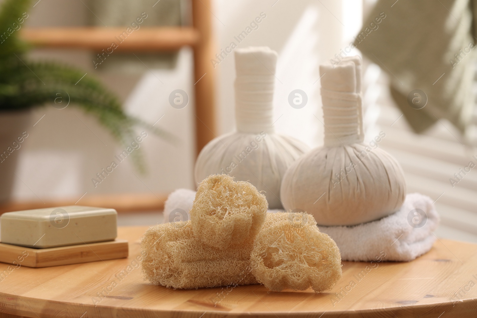 Photo of Loofah sponges, soap and herbal bags on wooden table indoors, closeup