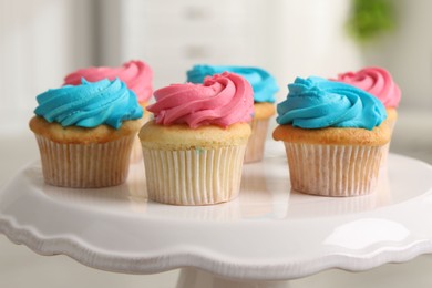 Photo of Delicious cupcakes with bright cream on dessert stand indoors, closeup