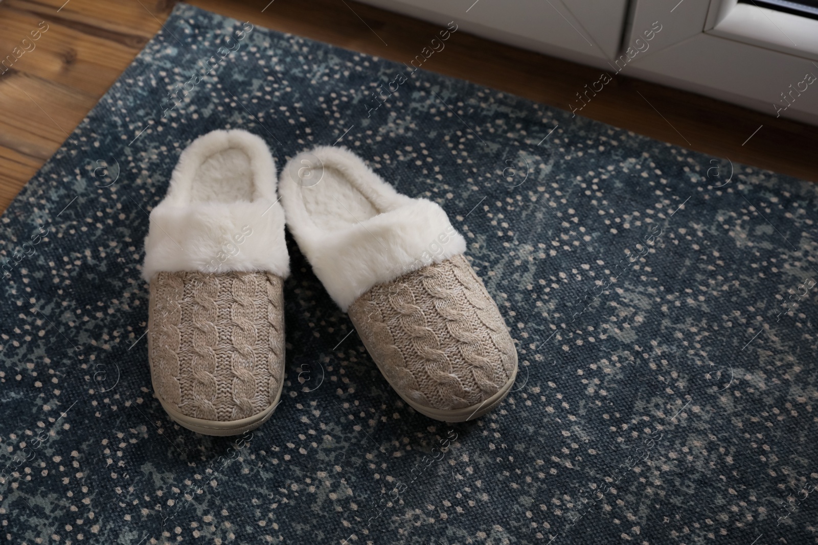 Photo of Pair of beautiful soft slippers on mat indoors. Space for text