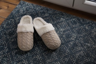 Pair of beautiful soft slippers on mat indoors. Space for text