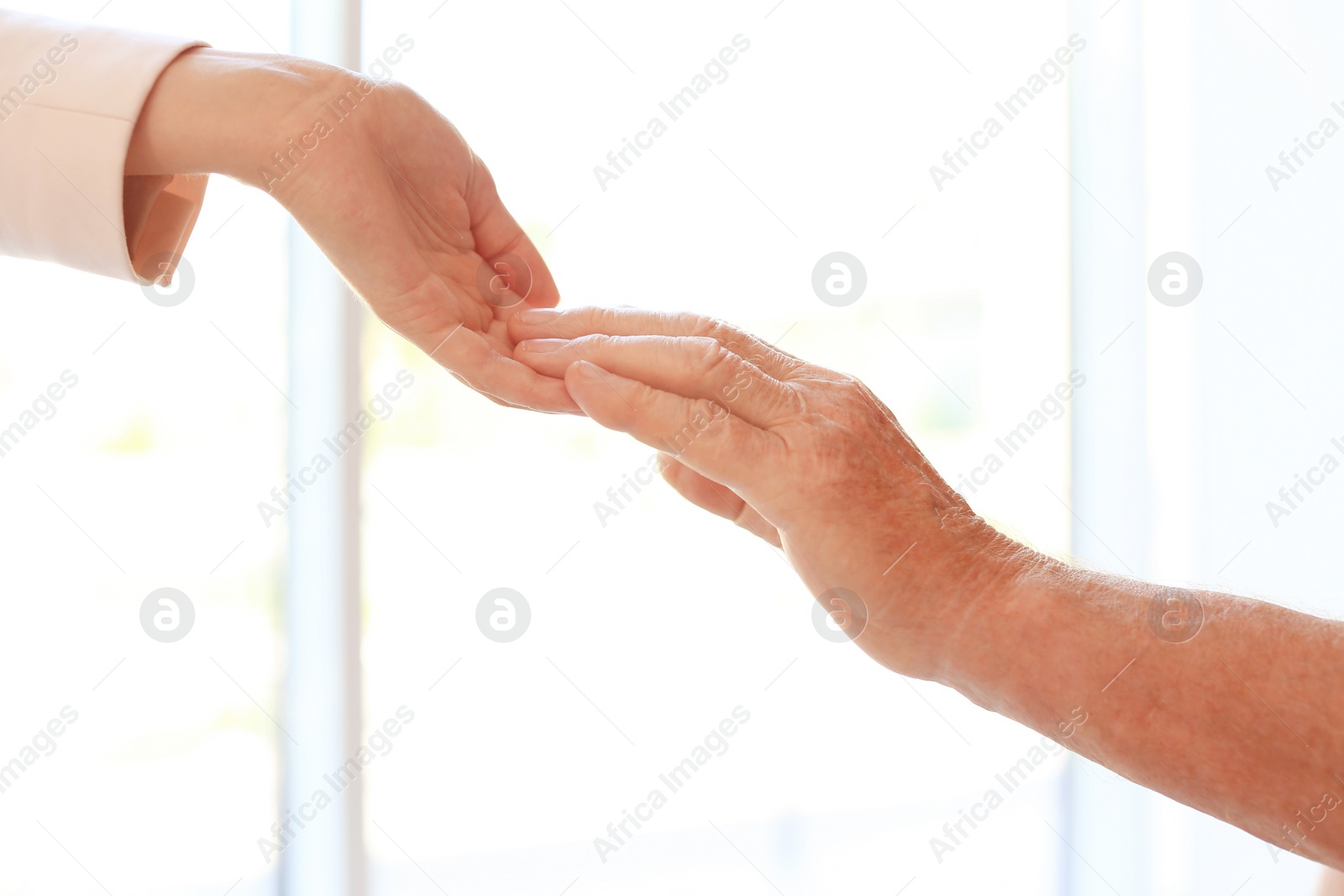 Photo of Helping hands on blurred background, closeup. Elderly care concept