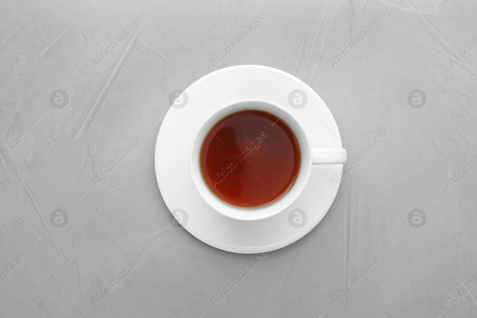 Photo of Cup of tea and saucer on grey background, top view