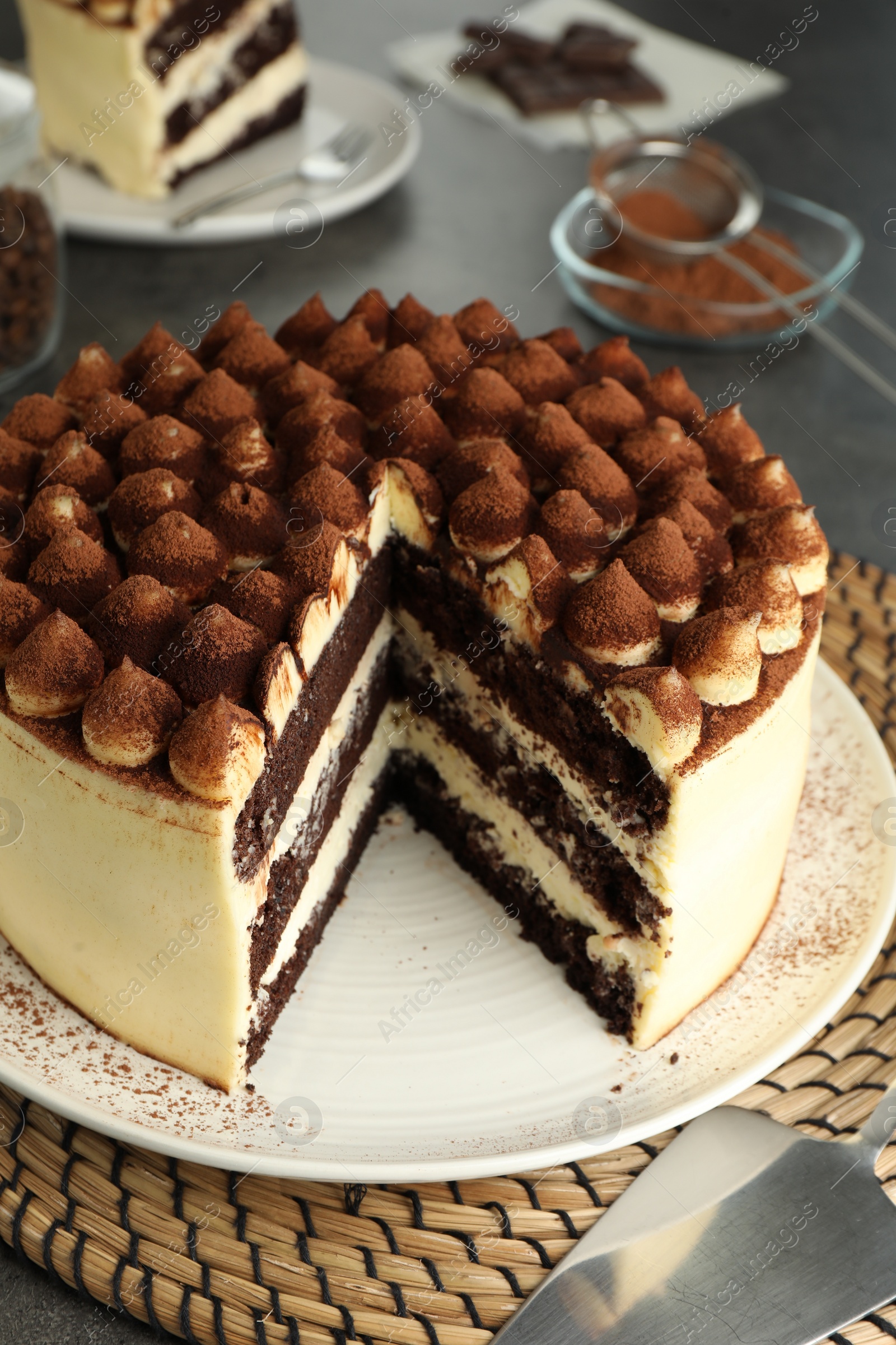 Photo of Delicious tiramisu cake with cocoa powder on grey table