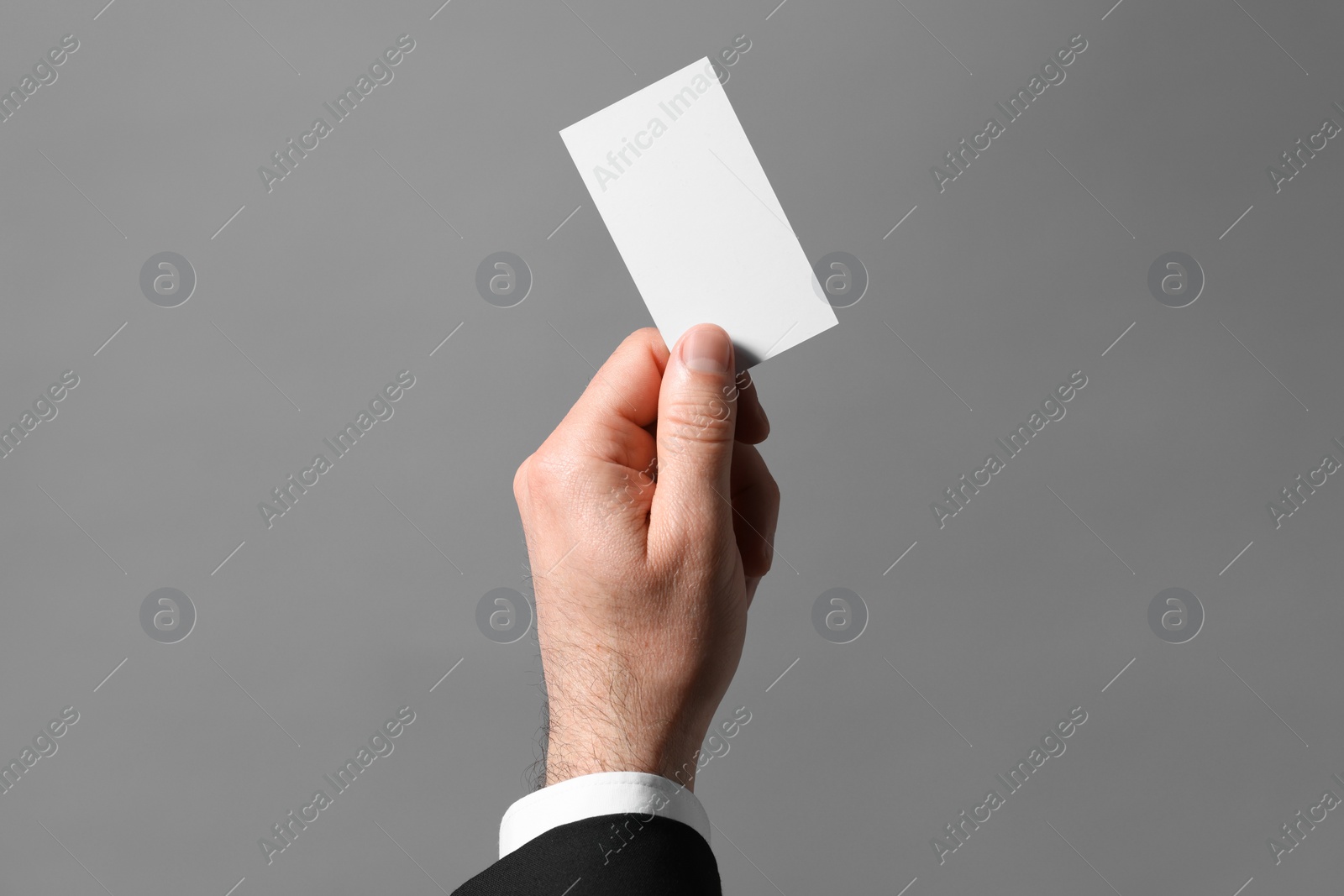 Photo of Man holding blank business card on grey background, closeup