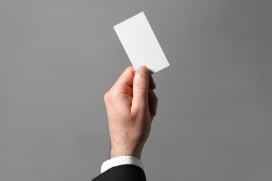 Photo of Man holding blank business card on grey background, closeup