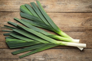 Photo of Fresh raw leeks on wooden table, flat lay