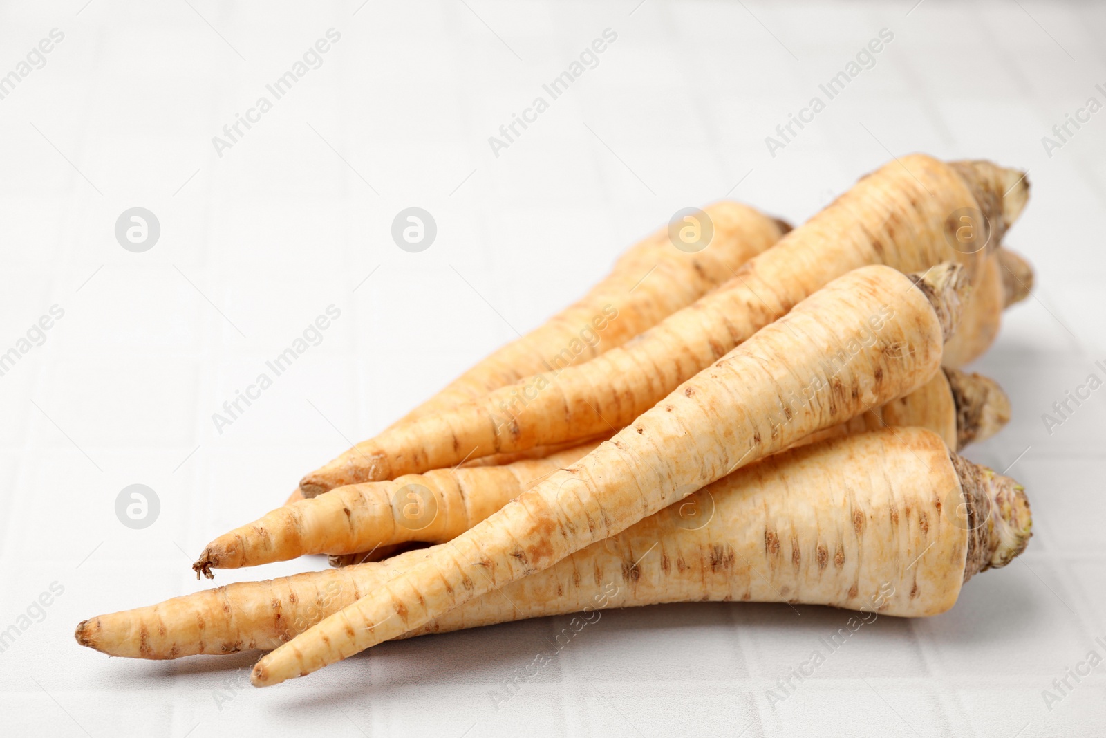 Photo of Raw parsley roots on white table, closeup