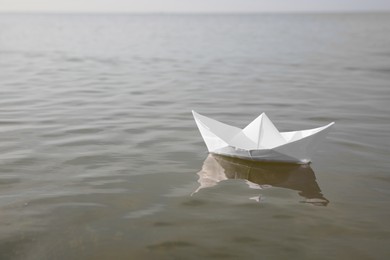 Photo of White paper boat on water surface, space for text