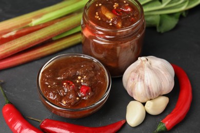 Tasty rhubarb sauce and ingredients on black table