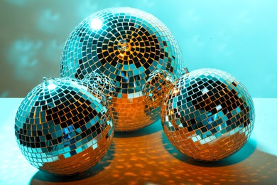 Photo of Three shiny disco balls on turquoise background