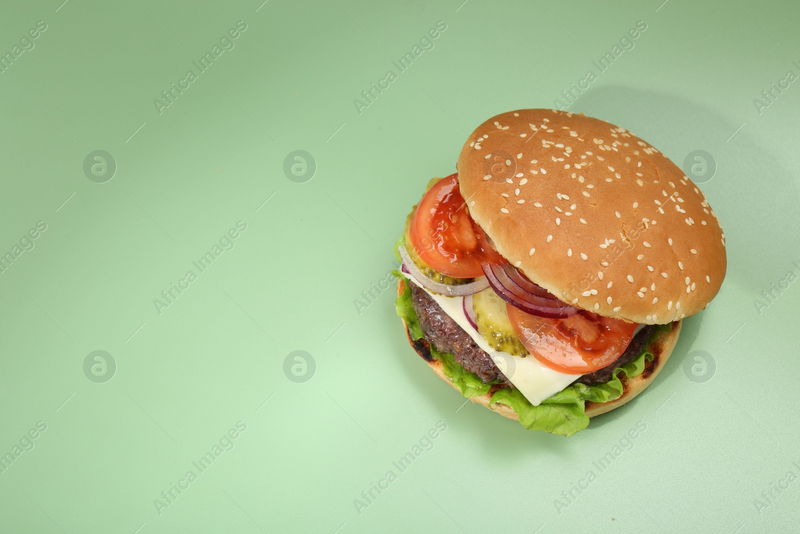 Photo of Burger with delicious patty on green background, top view. Space for text