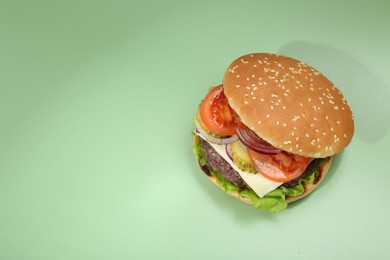 Photo of Burger with delicious patty on green background, top view. Space for text