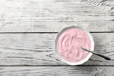 Bowl with tasty yogurt on wooden background