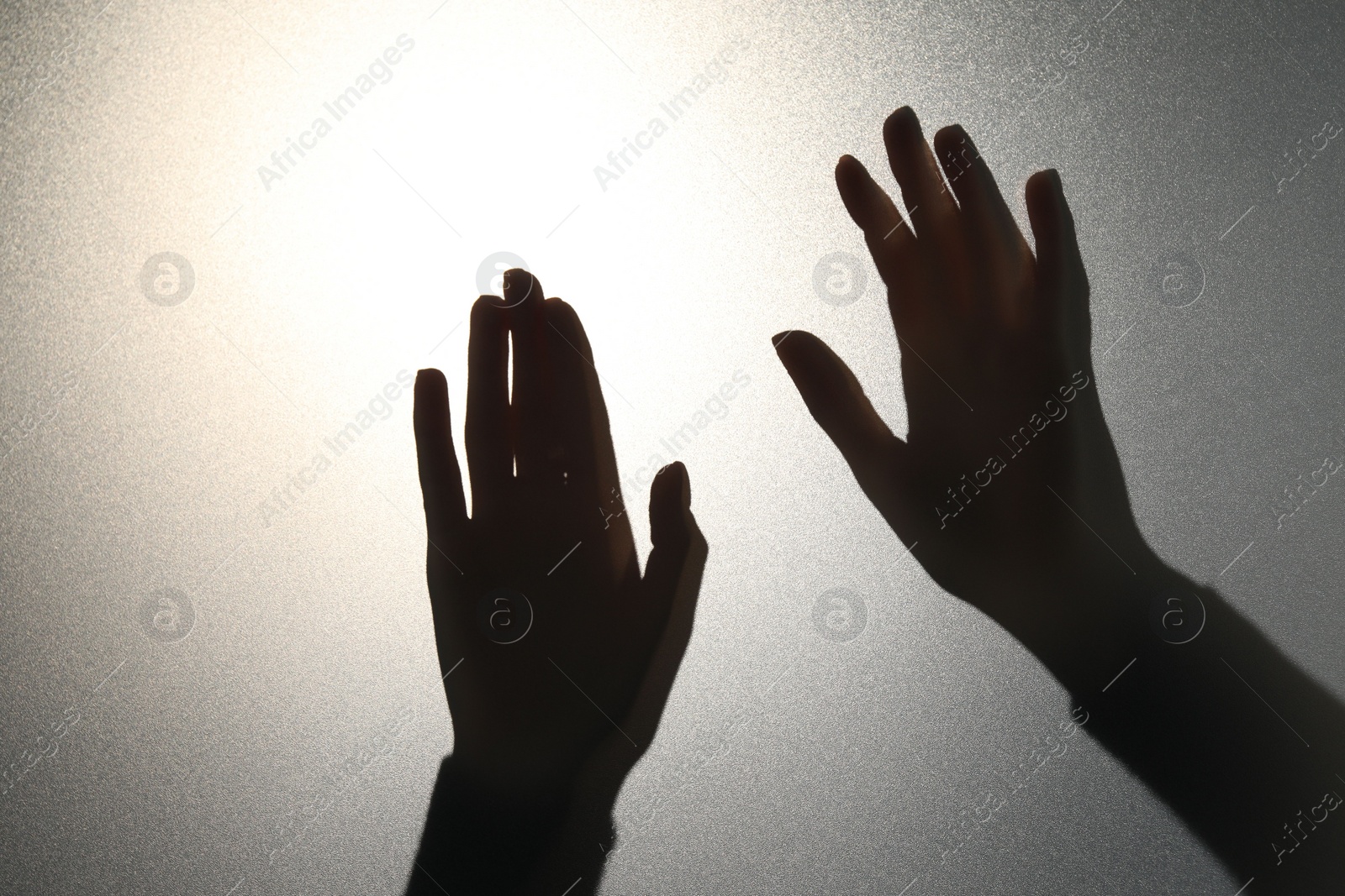 Photo of Silhouette of ghost behind glass against light grey background, closeup