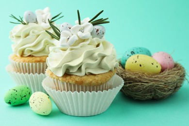 Photo of Tasty Easter cupcakes with vanilla cream and festive decor on turquoise background