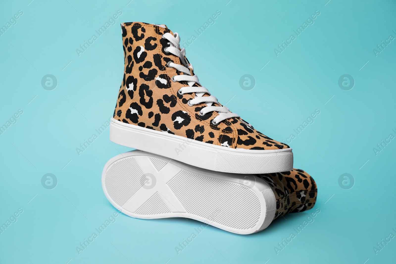 Photo of Pair of classic old school sneakers with leopard print on light blue background