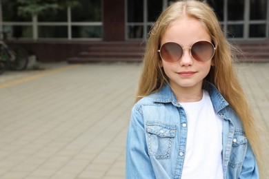 Girl wearing stylish sunglasses on street, space for text