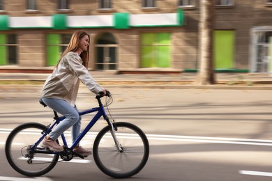 Image of Happy beautiful woman riding bicycle in city, motion blur effect