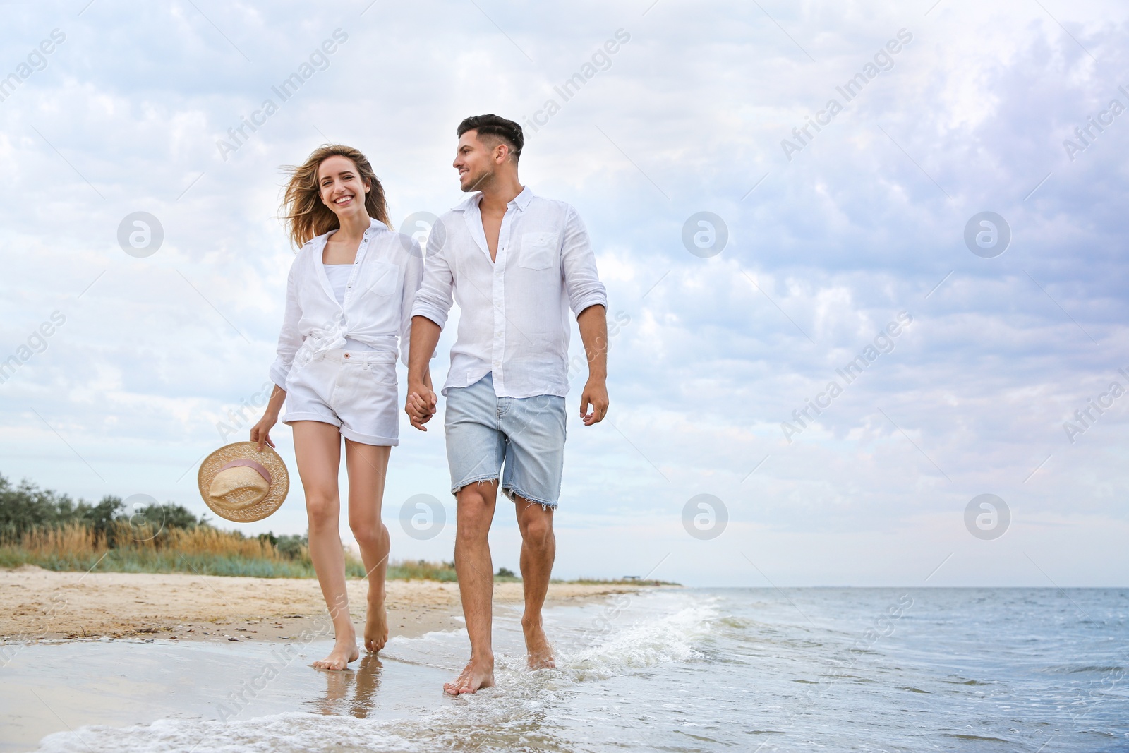 Photo of Happy couple having romantic walk on beach. Space for text