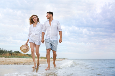 Happy couple having romantic walk on beach. Space for text