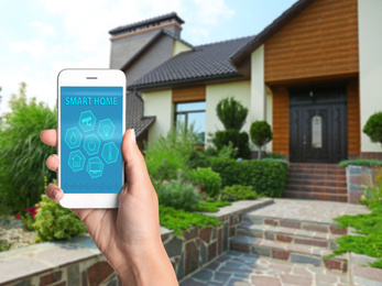 Woman using home security app on smartphone outdoors, closeup. Space for text