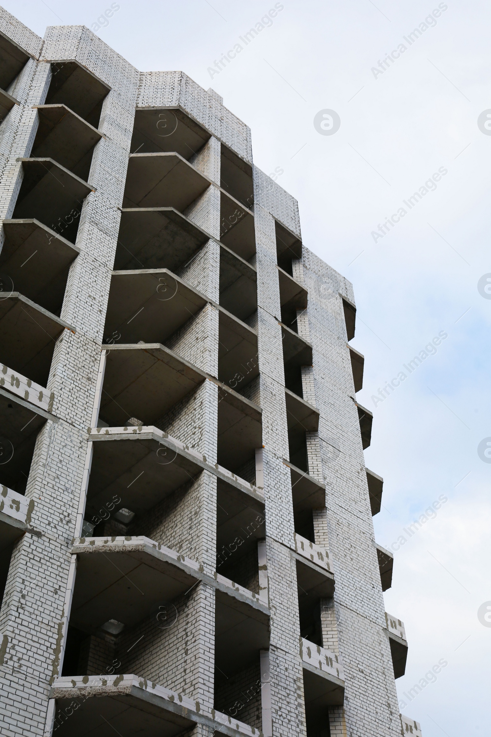 Photo of Construction site with unfinished building under cloudy sky, low angle view