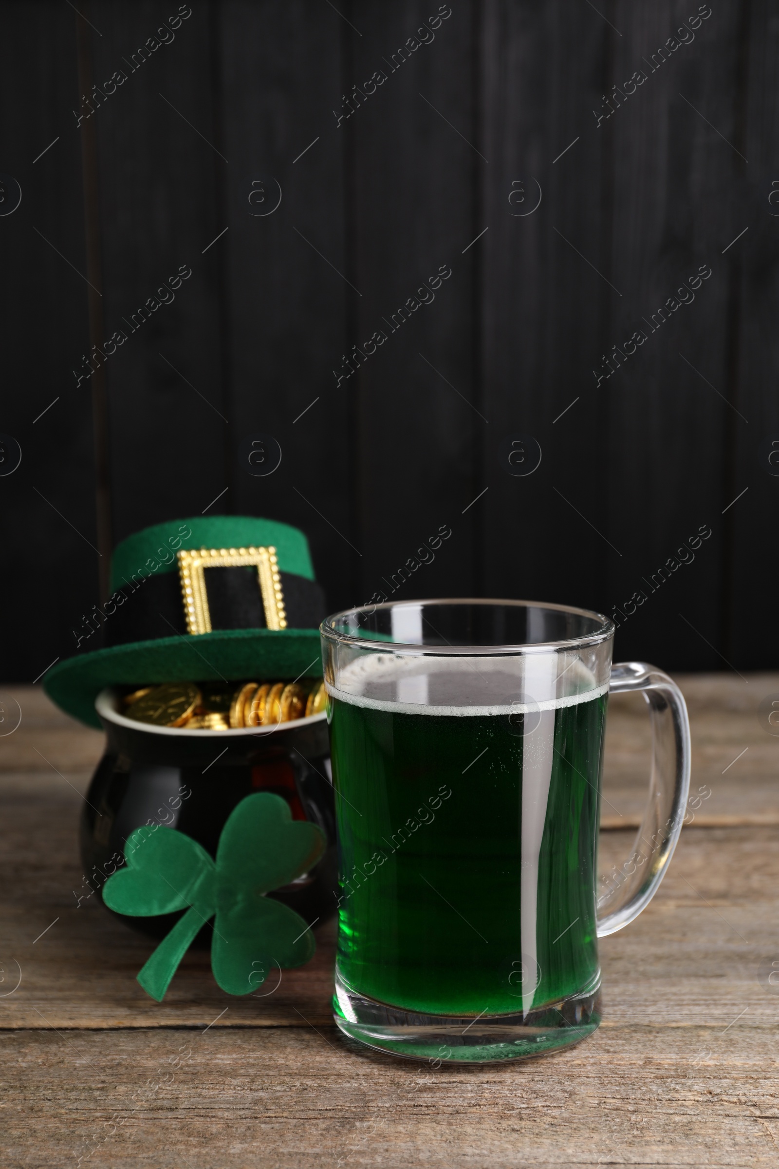 Photo of St. Patrick's day celebration. Green beer, leprechaun hat, pot of gold and decorative clover leaf on wooden table. Space for text