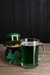 Photo of St. Patrick's day celebration. Green beer, leprechaun hat, pot of gold and decorative clover leaf on wooden table. Space for text