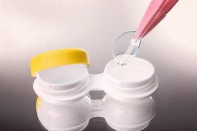 Photo of Taking contact lens from case on grey background, closeup