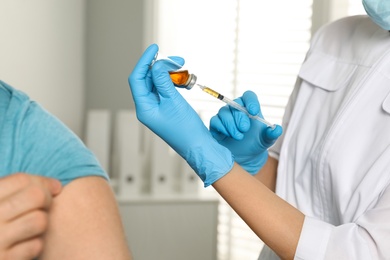 Doctor giving injection to patient in hospital, closeup. Vaccination day