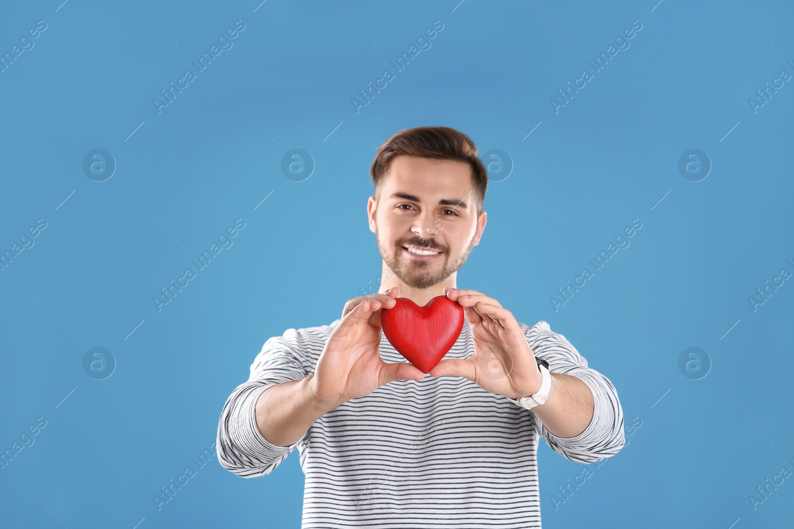 Photo of Man holding decorative heart on color background