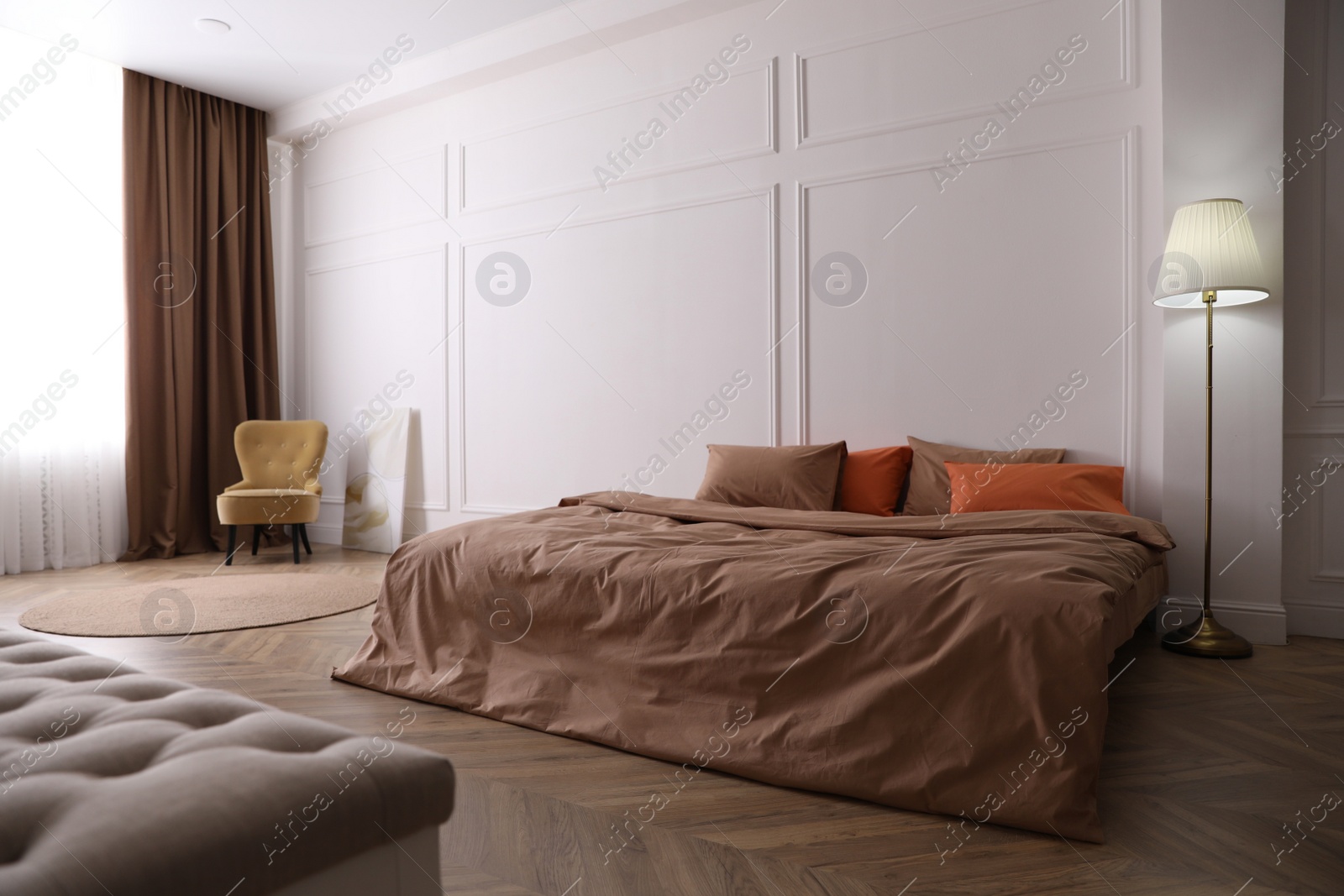 Photo of Bed with orange and brown linens in stylish room